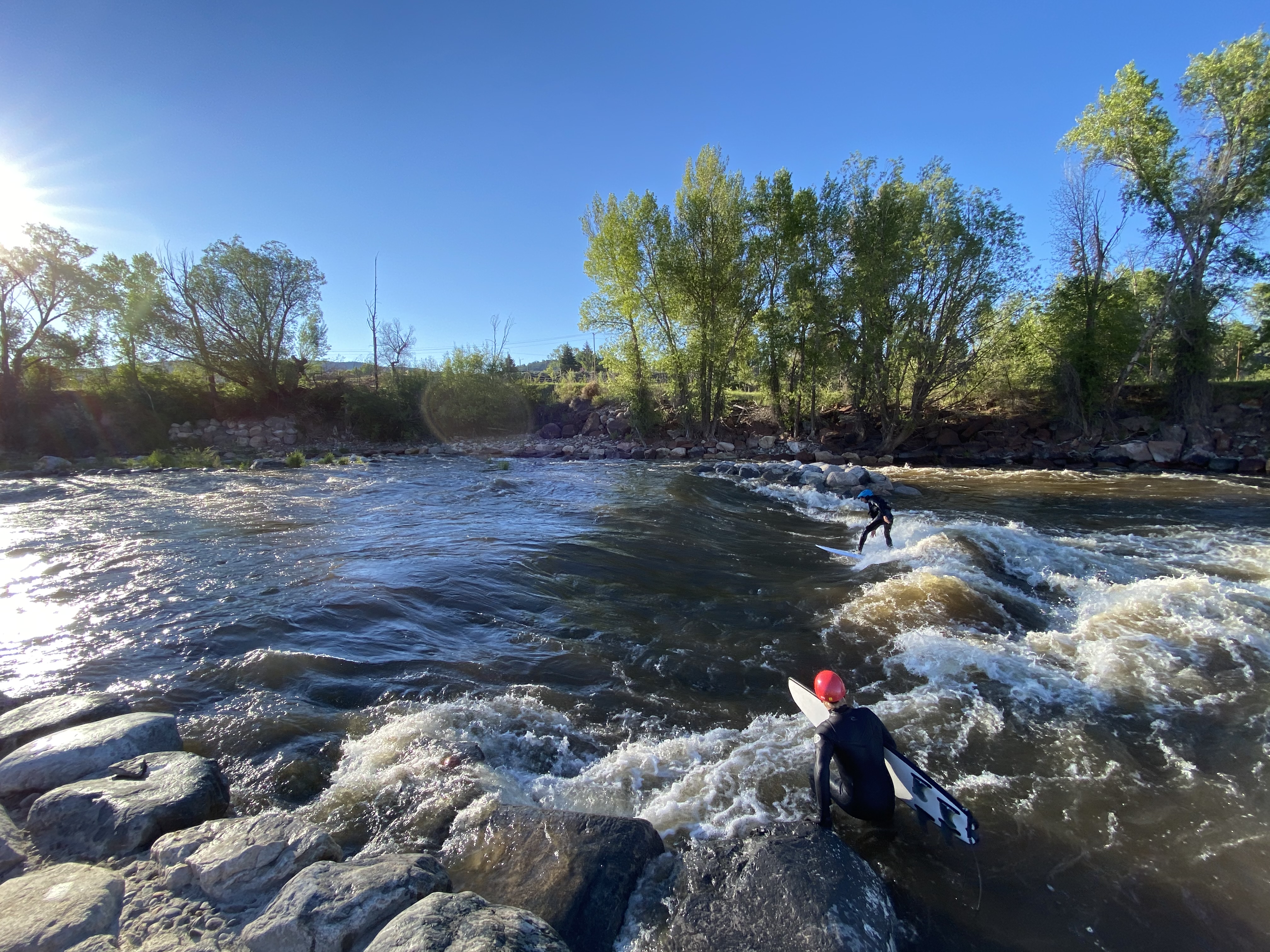 Surfers riding the Eagle River wave at golden hour