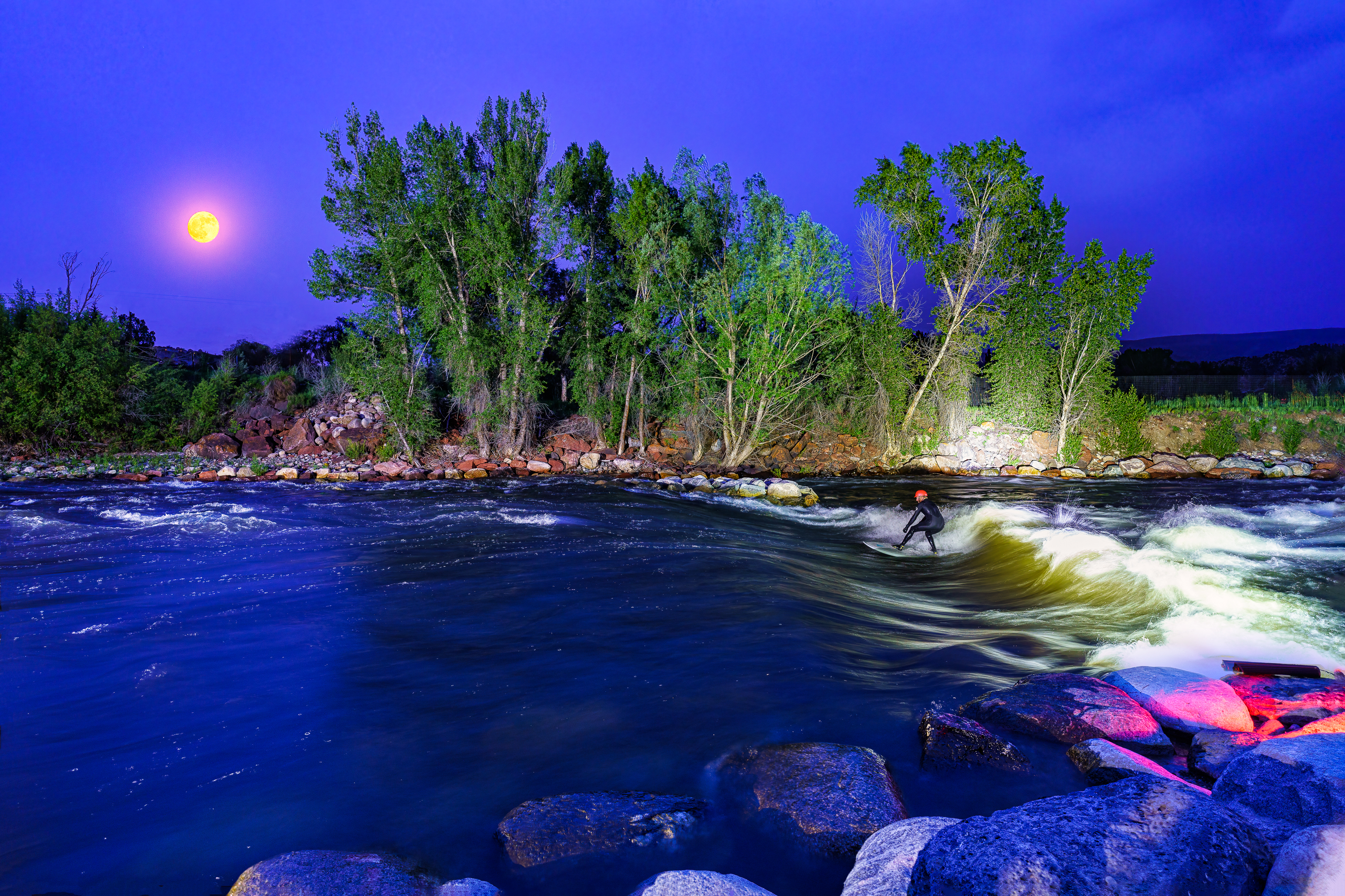 River surfer under a full moon on the Eagle River